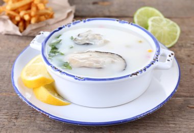 Tasty soup with oysters on wooden table clipart