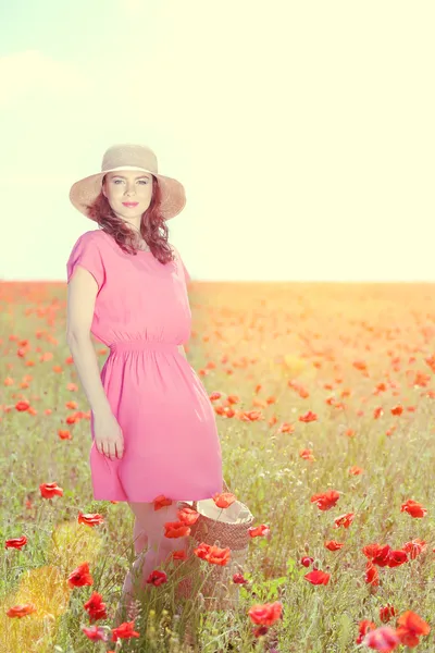 Beautiful young woman holding wicker bag in poppy field — Stock Photo, Image