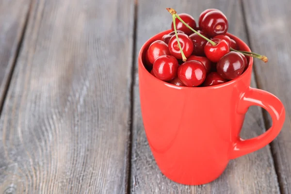 Süßkirschen im Becher auf Holzgrund — Stockfoto