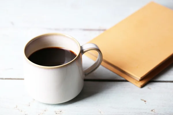 Copo com café quente e livro velho sobre fundo de madeira — Fotografia de Stock