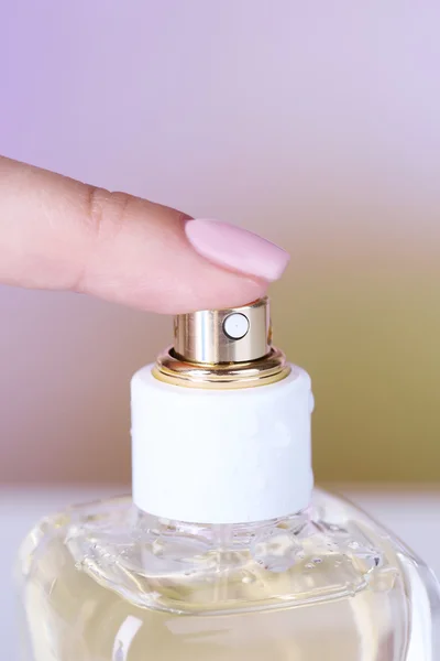 Bottle of perfume in hand on bright background