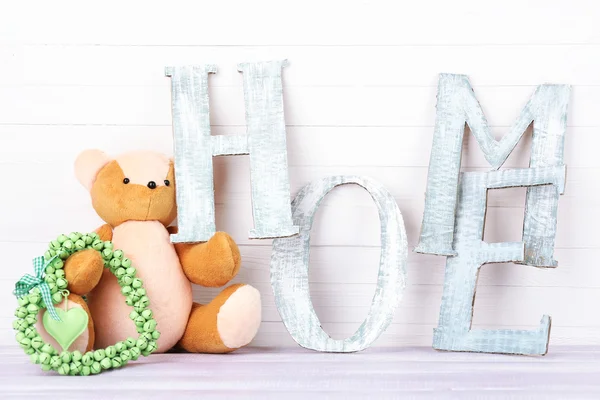 Letras decorativas formando palavra HOME com ursinho de pelúcia em fundo de madeira — Fotografia de Stock