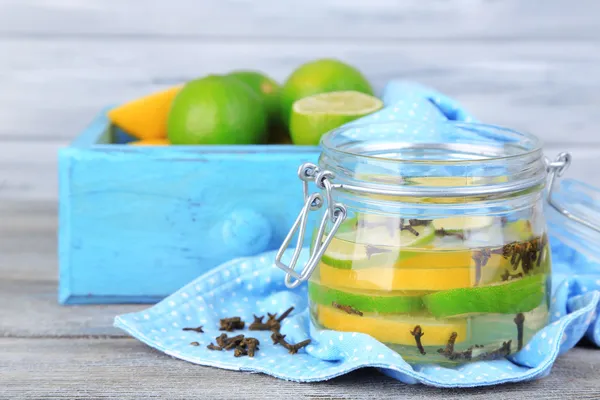 Inlagda limefrukterna och kryddnejlika i glasburk, på färg trä bakgrund — Stockfoto