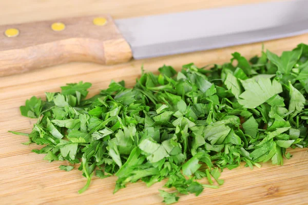 Chopped greens with knife on cutting board — Stock Photo, Image