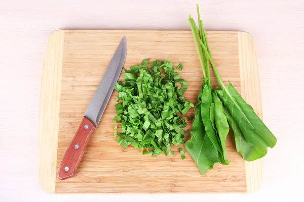 Verdes picados con cuchillo en tabla de cortar en la mesa — Foto de Stock