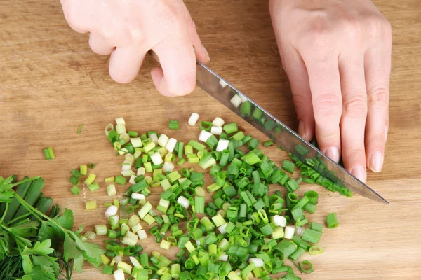 Female hand cutting chives on cutting board — Stock Photo, Image