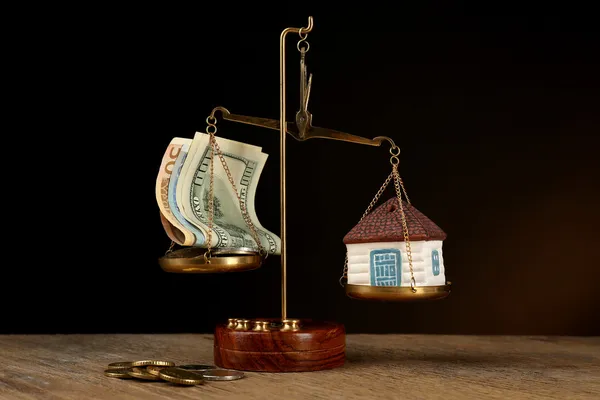 Scale with money and model of house on dark background — Stock Photo, Image