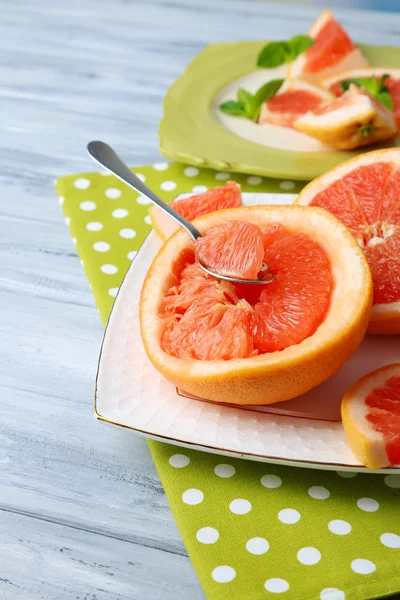 Ripe grapefruits on plate, on wooden table, on light background — Stock Photo, Image