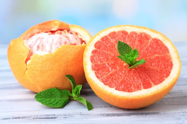 Mogen skalade grapefrukt på färg träbord, på ljus bakgrund — Stockfoto