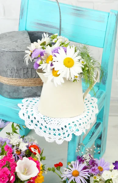 Strauß bunter Blumen in dekorativen Eimern, auf Stuhl, auf dem heimischen Innenhintergrund — Stockfoto