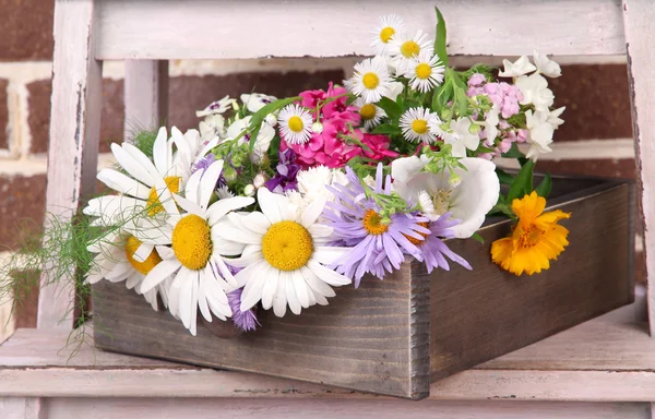 Schöne Blumen in Kiste auf kleiner Leiter auf Backsteinmauer Hintergrund — Stockfoto