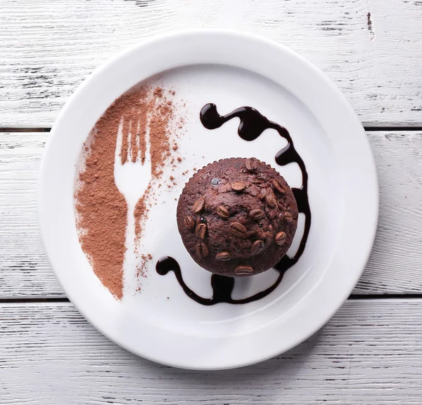 Muffin czekoladowy z sosem czekoladowym na talerzu, na tle drewniane — Zdjęcie stockowe