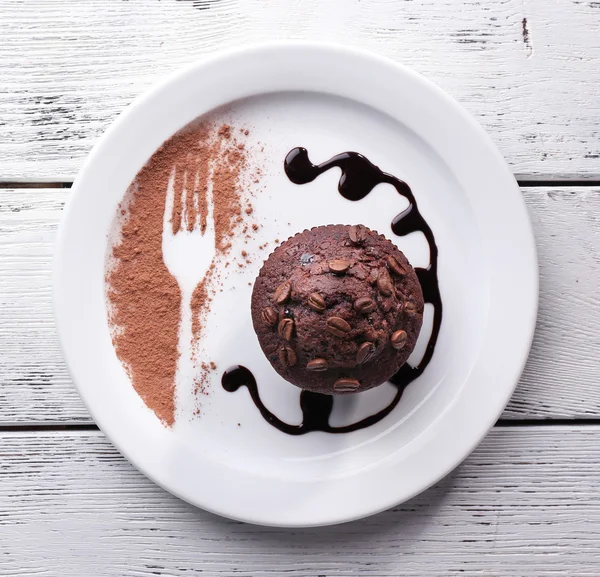 Magdalena de chocolate con salsa de chocolate en el plato, sobre fondo de madera — Foto de Stock