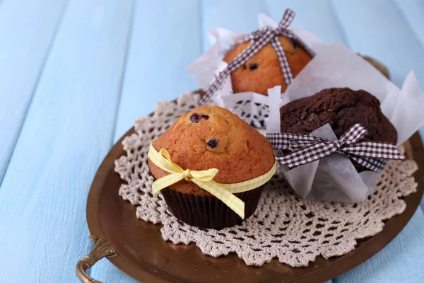 Smakelijke muffins op dienblad, op een houten achtergrond kleur — Stockfoto