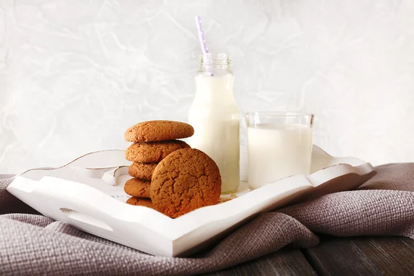 Mléko a soubory cookie v tabulce na světle šedém pozadí — Stock fotografie