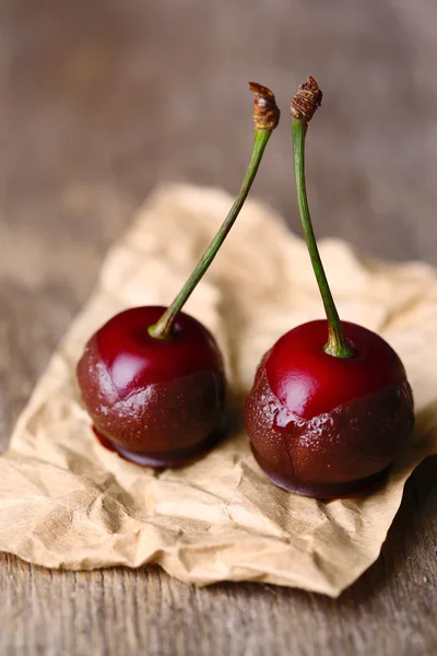 Sweet cherries with chocolate, on wooden background — Stock Photo, Image