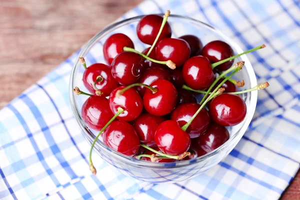 Cerezas en cuenco de color sobre fondo de madera — Foto de Stock