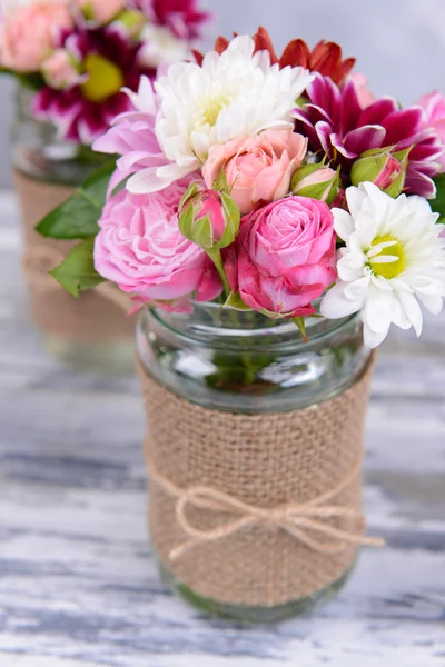 Piękny bukiet kwiatów jasny w słoiki na stole — Zdjęcie stockowe