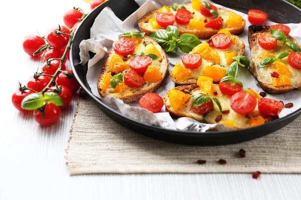 Tasty bruschetta with tomatoes in pan — Stock Photo, Image