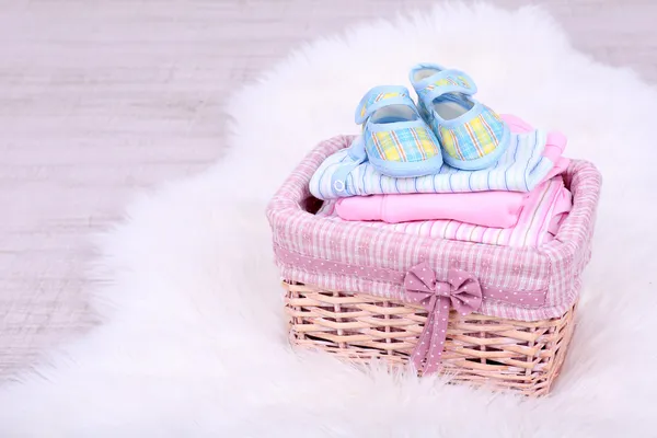 Baby clothes in basket on floor in room — Stock Photo, Image
