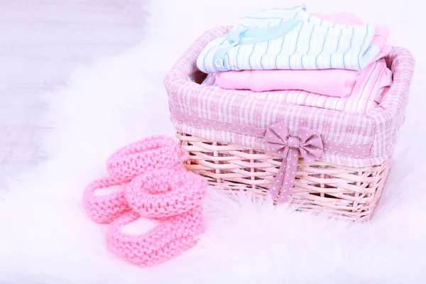 Baby clothes in basket on floor in room — Stock Photo, Image