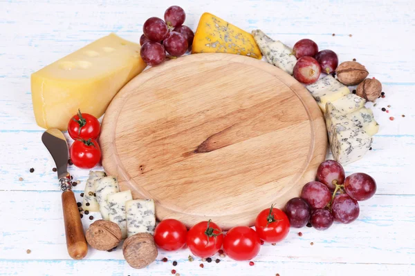 Different types of cheese with empty board — Stock Photo, Image