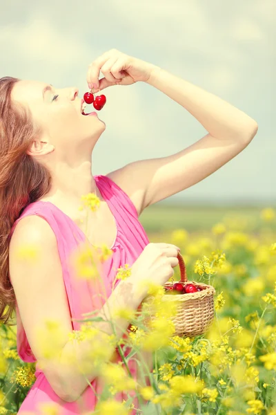 Mulher segurando cesta de vime com cerejas no campo — Fotografia de Stock