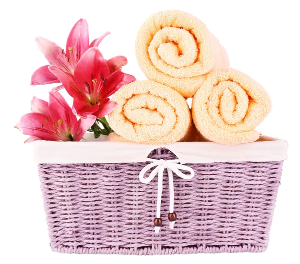 Color towels and lily flowers in wicket basket — Stock Photo, Image