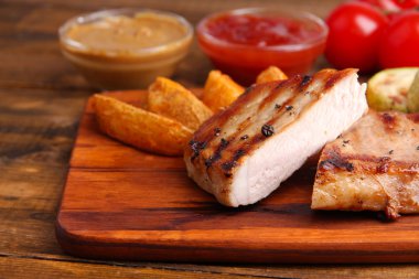 ızgara biftek, ızgara sebzeler ve kızarmış patates parçaları