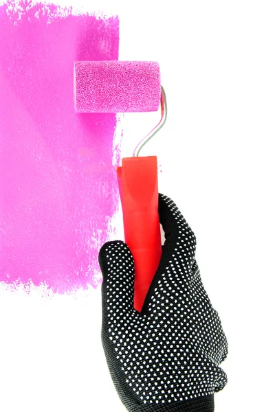 Roller brush with pink paint in hand — Stock Photo, Image