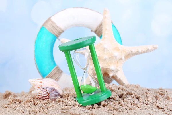 Hourglass in sand on blue sky background — Stock Photo, Image