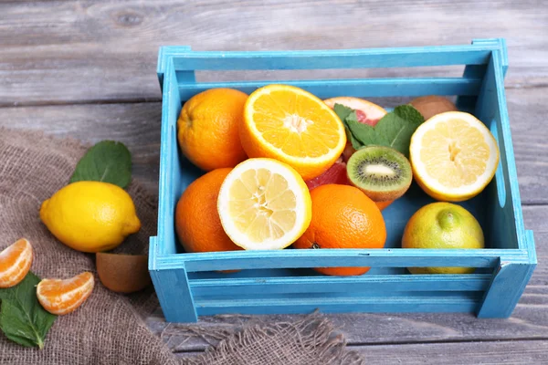 Frutas exóticas frescas con hojas verdes en caja de madera — Foto de Stock