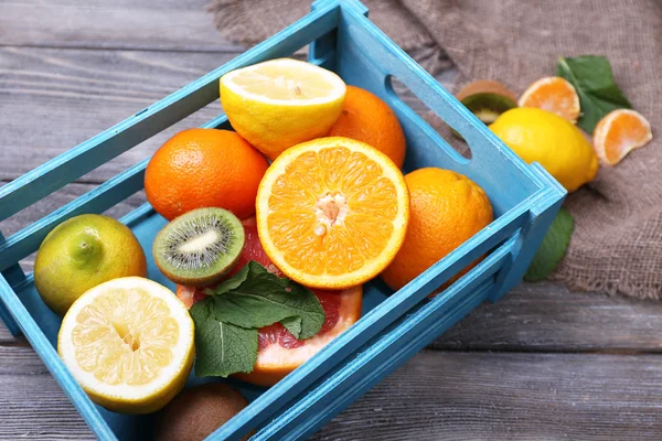 Frutas exóticas frescas con hojas verdes en caja de madera —  Fotos de Stock