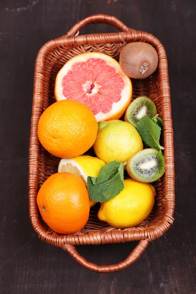 Frutas frescas exóticas con hojas verdes en canasta de mimbre — Foto de Stock