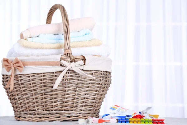 Colorful towels in basket and pins — Stock Photo, Image