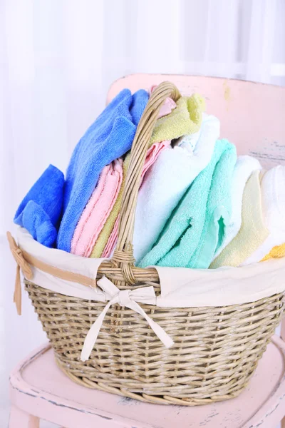 Colorful towels in basket on chair — Stock Photo, Image