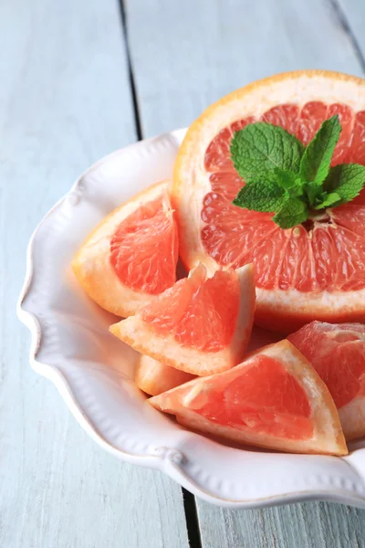 Rijp grapefruits op plaat op een houten achtergrond kleur — Stockfoto