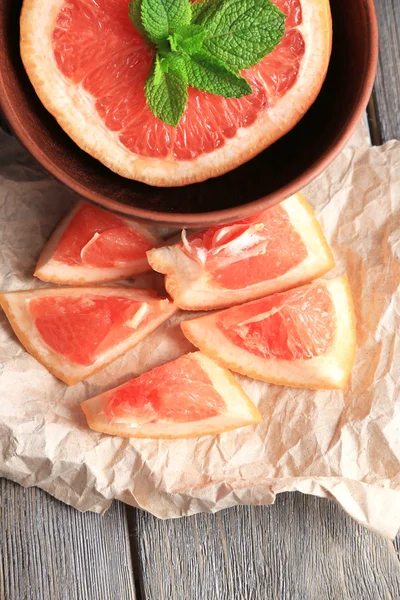 Součástí zralých grapefruitů v míse, na dřevěné pozadí — Stock fotografie