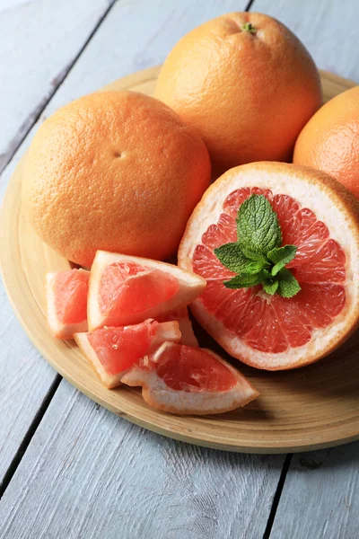 Mogen grapefrukt på plattan på färg trä bakgrund — Stockfoto
