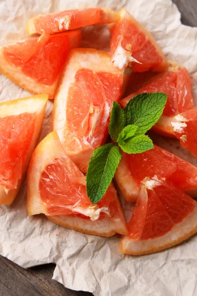 Zralé nasekané grapefruitu s mátou listy na dřevěné pozadí — Stock fotografie