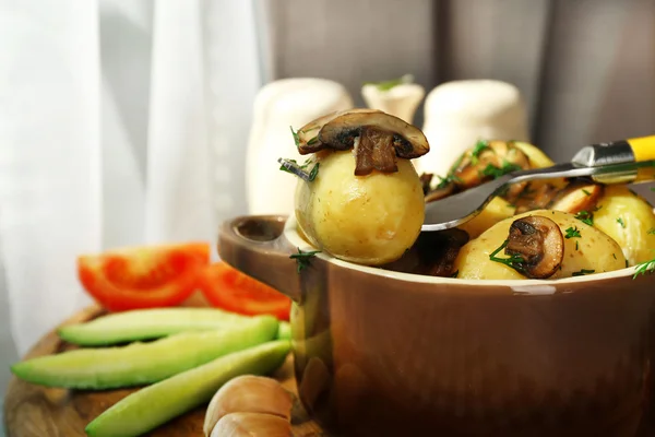 Jonge gekookte aardappelen in de pan met de groenten op tafel in de keuken — Stockfoto