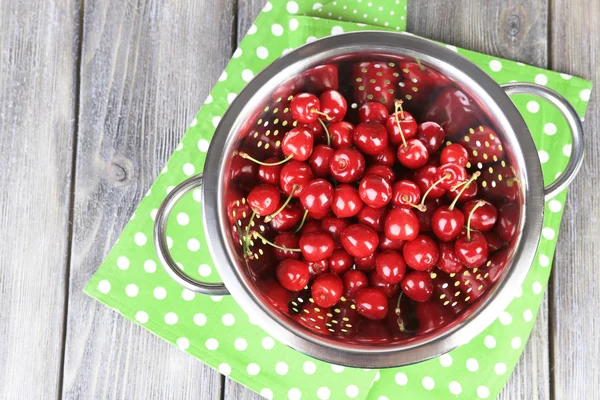 Cerezas dulces en colador sobre fondo de madera de color — Foto de Stock