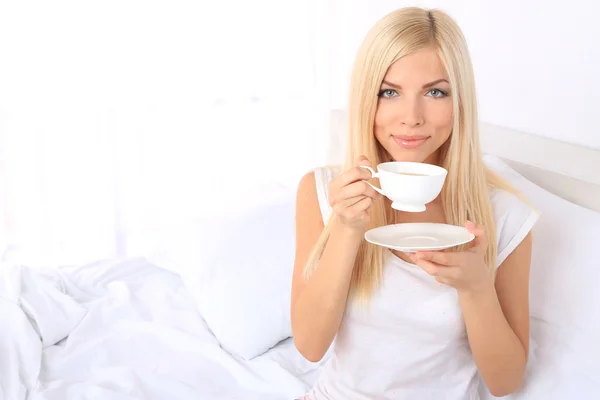 Όμορφη κοπέλα με φλιτζάνι τσάι στο κρεβάτι — Φωτογραφία Αρχείου