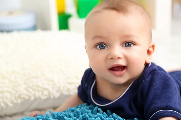 Cute baby boy lying on floor in room — Stock Photo, Image