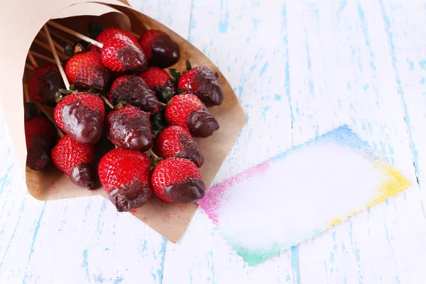 Strawberry in chocolate on skewers in paper bag on table close-up — Stock Photo, Image