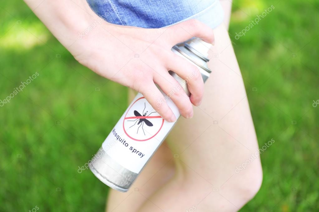 Woman spraying insect repellent on skin
