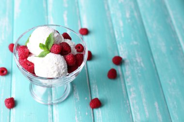 Kremalı dondurma ile Ahududu plaka renk ahşap zemin üzerinde cam kase