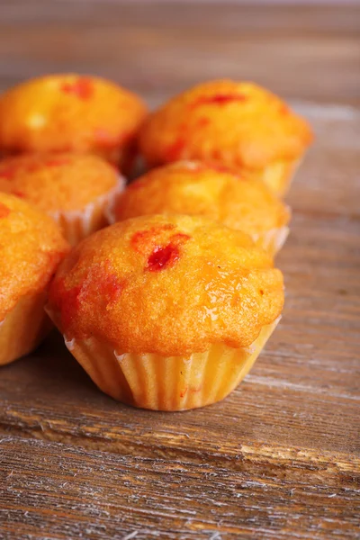 Muffins saborosos com groselha vermelha no fundo de madeira — Fotografia de Stock