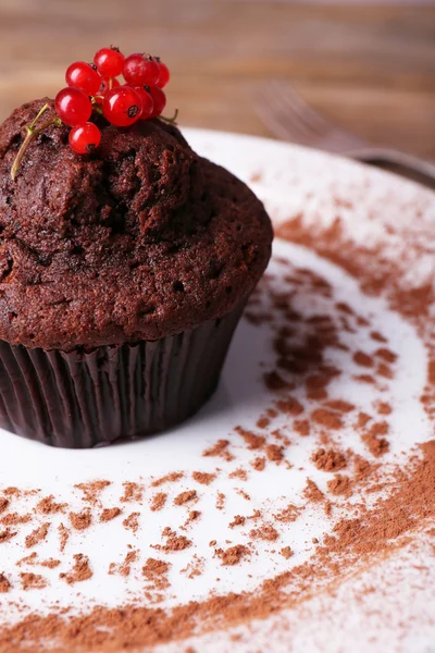 Chocolate muffin with red currant on plate on wooden background — Stock Photo, Image