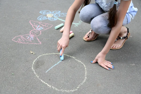 Cute girl drawing with chalk on asphalt — Stock Photo, Image